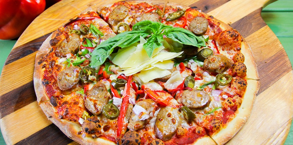 A hot sausage pizza topped with fresh basil.