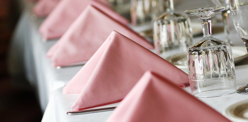 Place settings with pink cloth napkins and crystal glasses