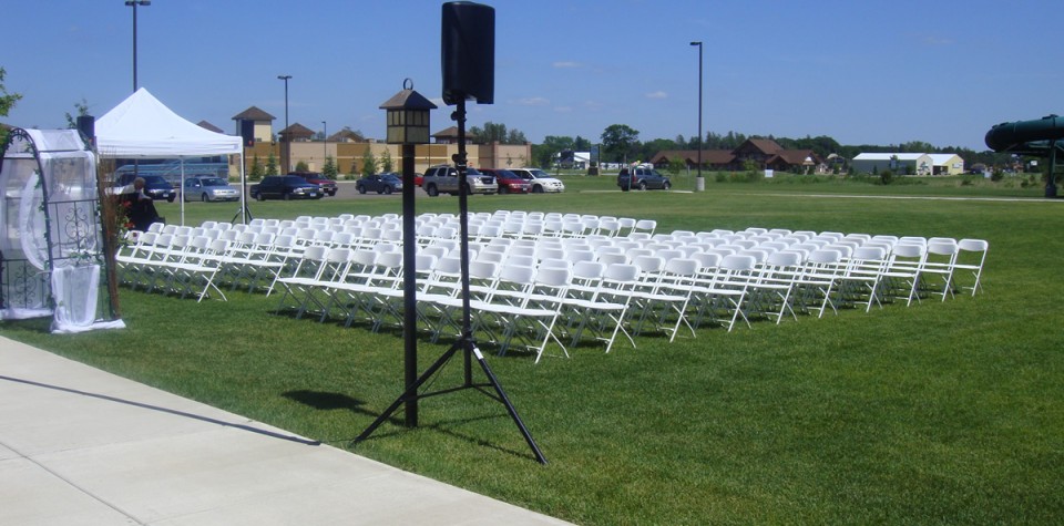Outdoor wedding ceremony setup with lots of white chairs on the grass